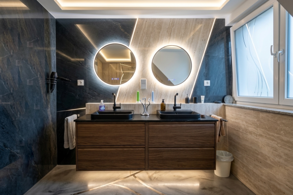Modernisierung von Badezimmermöbeln Modernes Badezimmer mit neu montierten Waschbeckenschränken, Waschbecken und beleuchteten Rundspiegeln.