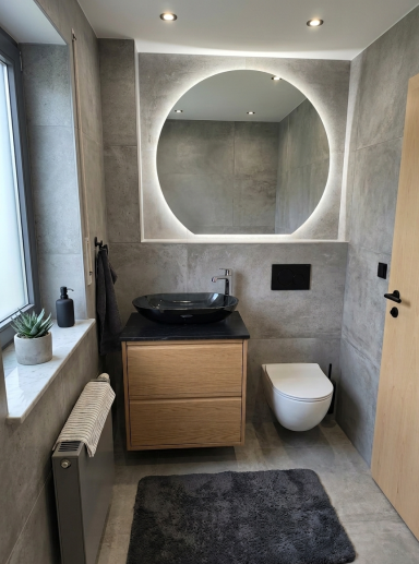 Modernes Badezimmer mit
montiertem Aufsatzwaschbecken. Unterschrank, LED-Spiegel und WC-Betätigungsplatte.